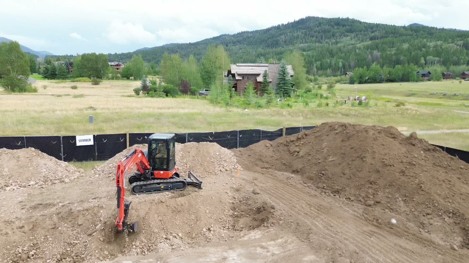 Mini excavator digging into a dirt pile, from the drone